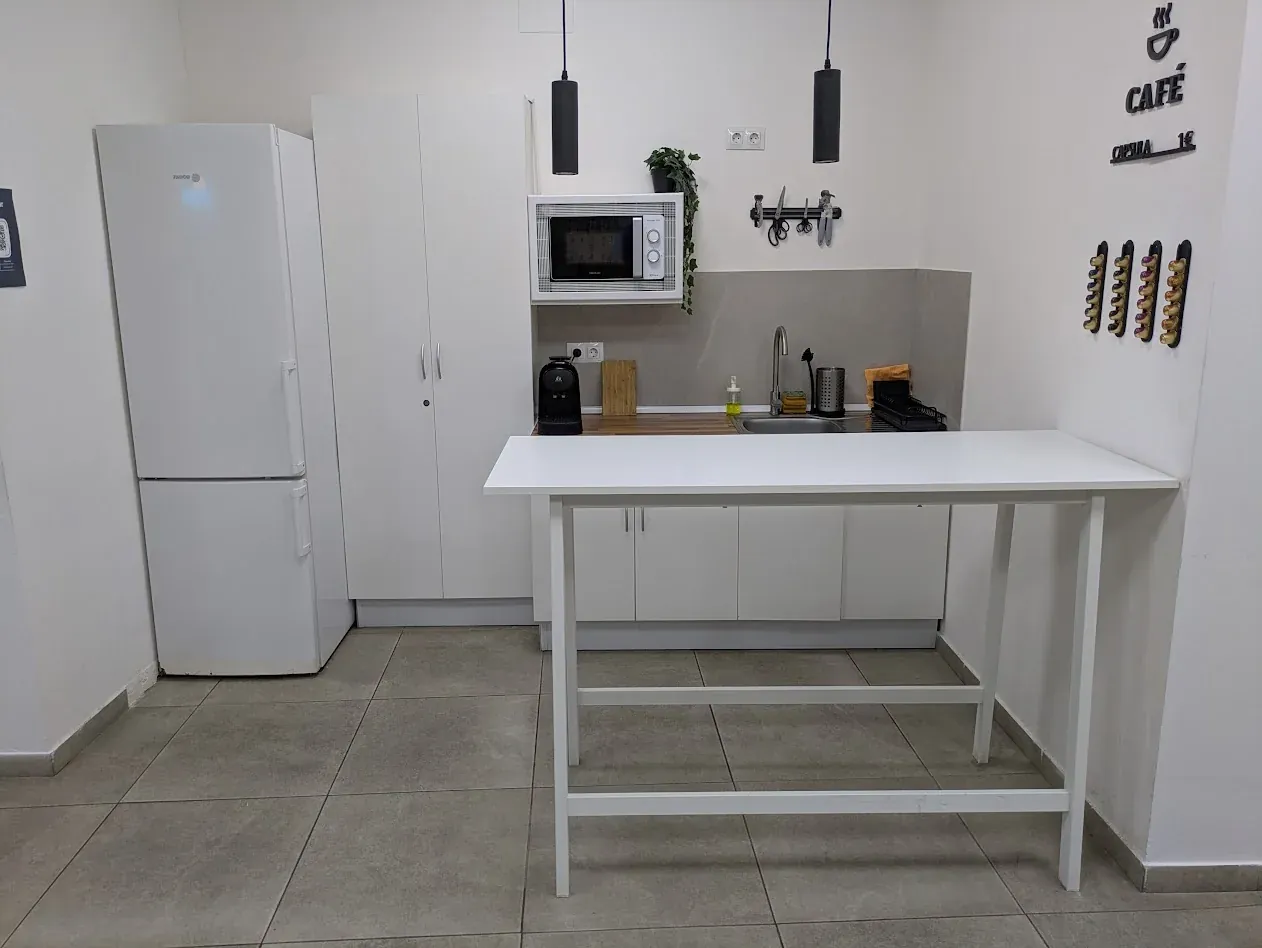 Cocina de apoyo actual con nevera, microondas y mesa auxiliar